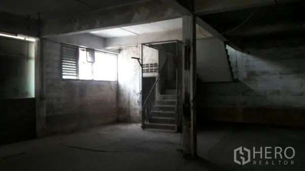 Factory for rent in Lam Luk Ka, Pathum Thani - Ground-floor production area with louvered windows and a concrete stairway inside the factory.