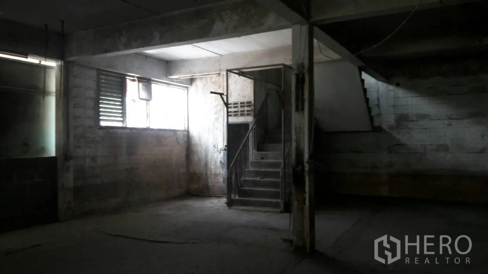 Factory for rent in Lam Luk Ka, Pathum Thani - Ground-floor production area with louvered windows and a concrete stairway inside the factory.