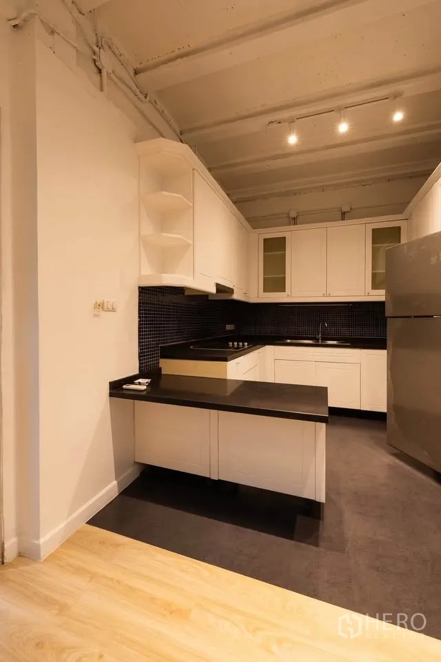 联排别墅 出租在Khlong Toei, Bangkok - U形厨房，黑色台面、马赛克墙面与不锈钢冰箱。