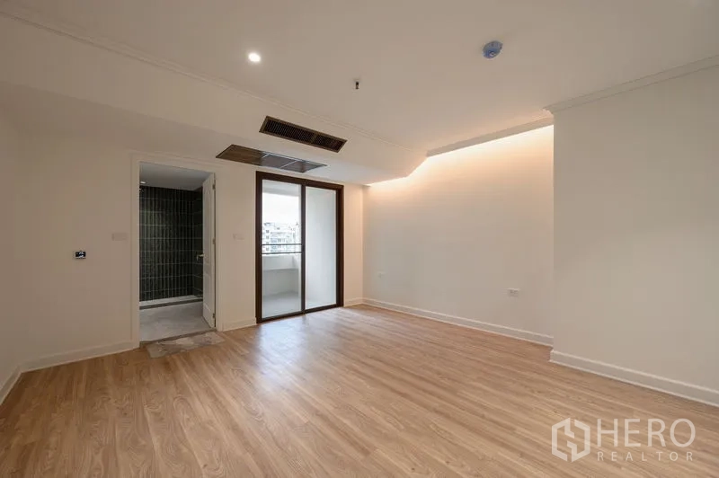 Condominium for sale in Watthana, Bangkok - Bedroom with cove lighting and balcony access next to an en-suite bathroom.