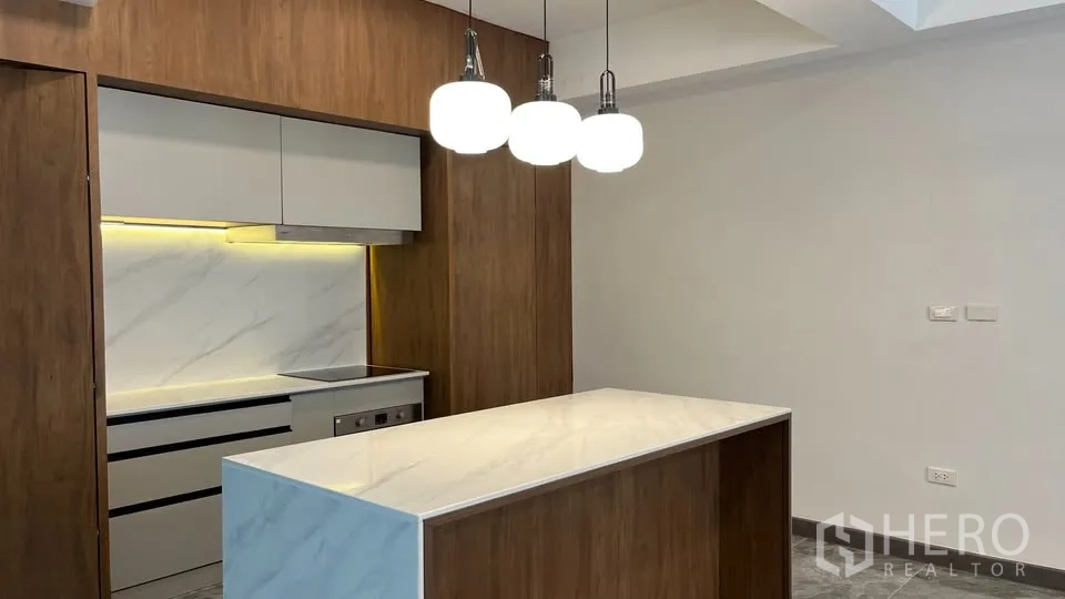 Home Office for rent in Watthana, Bangkok - Modern Western kitchen with a white marble island, wood cabinetry and pendant lights.