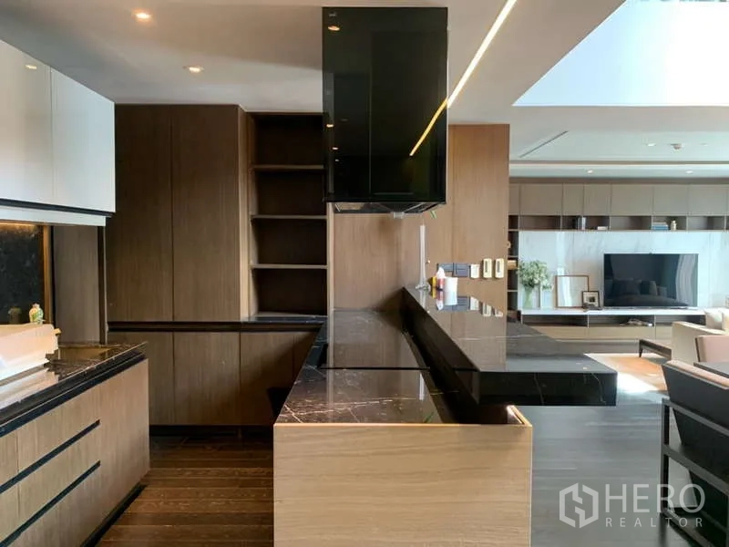 Condominium for rent in Khlong Toei, Bangkok - Modern open kitchen with black marble countertops, wood cabinetry and an island bar adjoining the lounge.