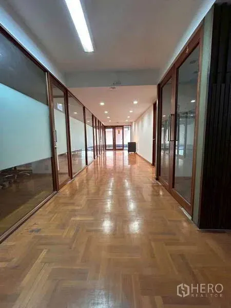 Home Office for rent or sale in Bang Phli, Samut Prakan - Long corridor with polished wood parquet floors, recessed lights and glass-partition offices on both sides.