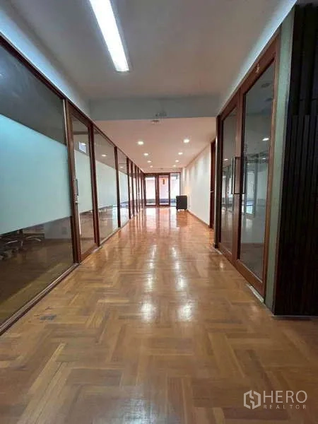 Home Office for rent or sale in Bang Phli, Samut Prakan - Long corridor with polished wood parquet floors, recessed lights and glass-partition offices on both sides.