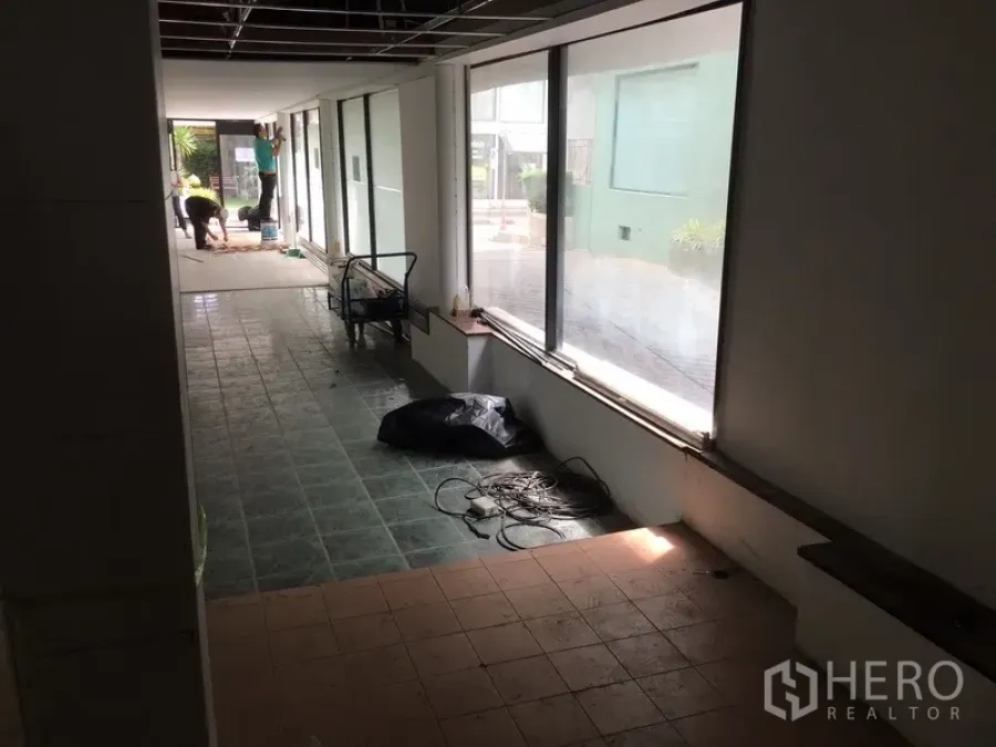 零售空间 出租在Watthana, Bangkok - 长条形室内零售空间，整面落地窗与瓷砖地面，采光充足，正在翻新。