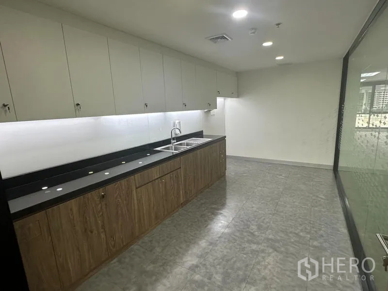 办公空间 出租在Khlong Toei, Bangkok - 配备长台面与水槽的办公室茶水间，上方设吊顶灯与壁柜。