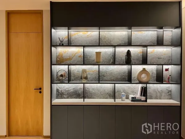 Detached House for rent or sale in Bang Kapi, Bangkok - Built-in illuminated display shelves with stone backsplashes beside a wooden door.