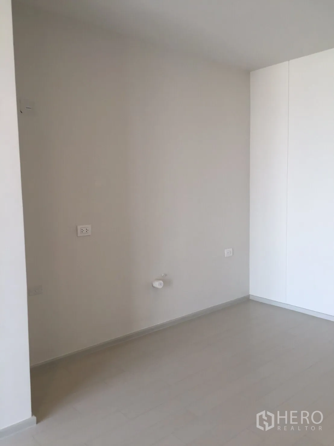 Condominium for sale in Pathum Wan, Bangkok - Bright bedroom corner with light flooring, power outlets, and built-in wardrobe.