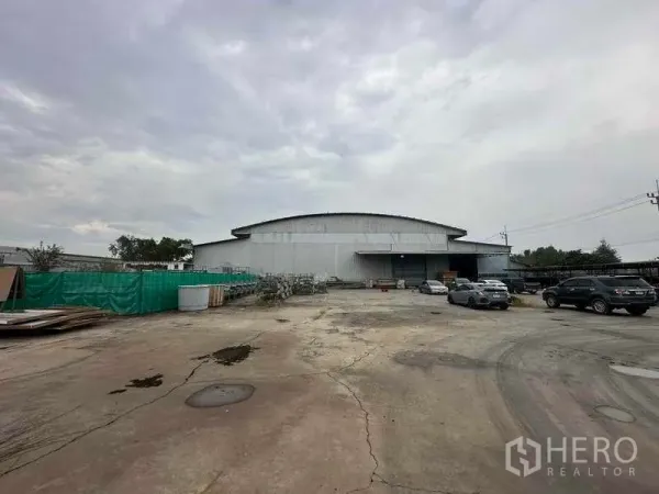 โรงงาน ให้เช่าในPathum Thani - มุมมองภายนอกโรงงานโครงสร้างเหล็กขนาดใหญ่ พร้อมลานคอนกรีตกว้างและที่จอดรถ