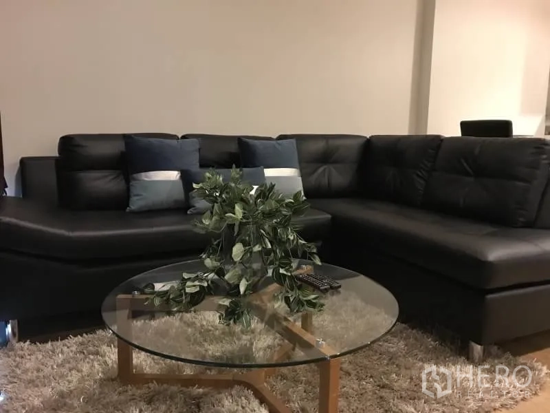 คอนโด ให้เช่าในKhlong Toei, Bangkok - ห้องนั่งเล่นร่วมสมัย โซฟาหนังรูปตัว L โต๊ะกลางกระจก และพรมขนฟู