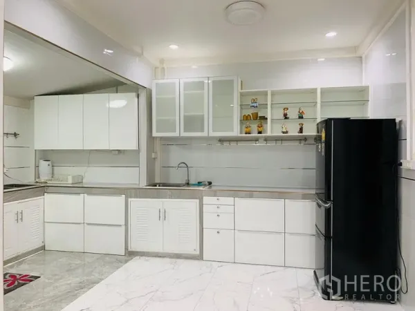 Detached House for sale in Din Daeng, Bangkok - Bright white kitchen with ample cabinets, stainless countertops and black fridge.