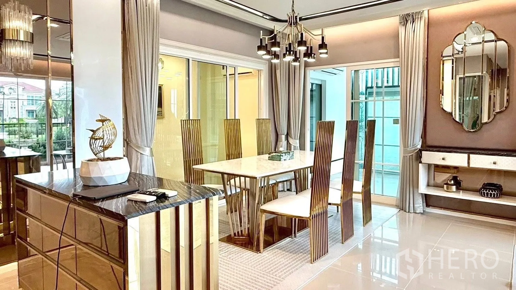 Detached House for rent or sale in Bueng Kum, Bangkok - Dining area with marble table, six gold chairs, designer chandelier and glass doors.