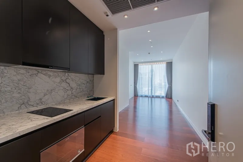 公寓 出售在Watthana, Bangkok - 走廊式厨房，黑色橱柜、大理石防溅板、电磁炉与嵌入式烤箱。