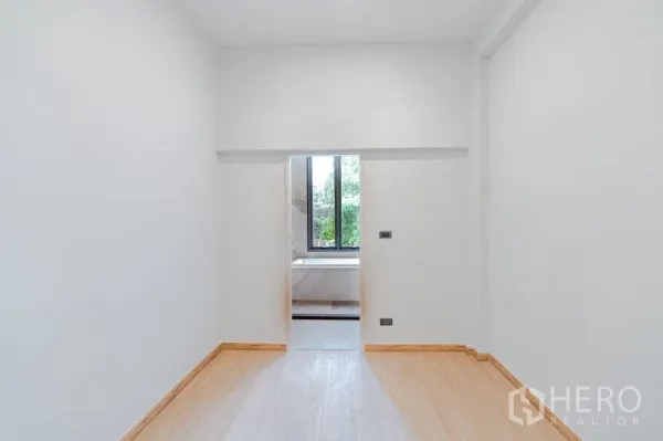 Townhouse for sale - Minimal bedroom with wood flooring and doorway to an ensuite bathroom with window view.