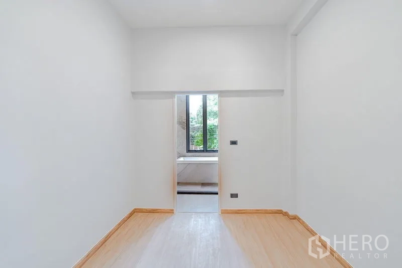 Townhouse for sale - Minimal bedroom with wood flooring and doorway to an ensuite bathroom with window view.