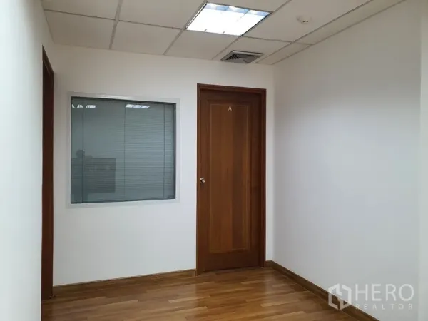 Office Space for rent in Watthana, Bangkok - Corridor of an office suite with a wooden door and an internal glass window with blinds.