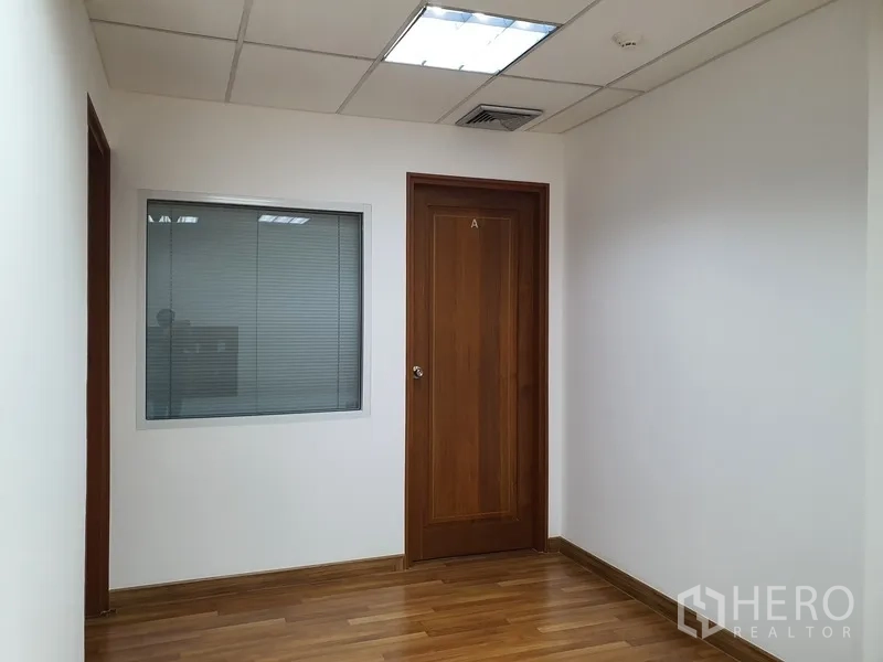 Office Space for rent in Watthana, Bangkok - Corridor of an office suite with a wooden door and an internal glass window with blinds.