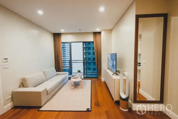 คอนโด ให้เช่าในKhlong Toei, Bangkok - ห้องนั่งเล่นสว่าง โซฟา ตู้ทีวี พื้นไม้ และประตูกระจกสไลด์ออกสู่ระเบียงวิวเมือง