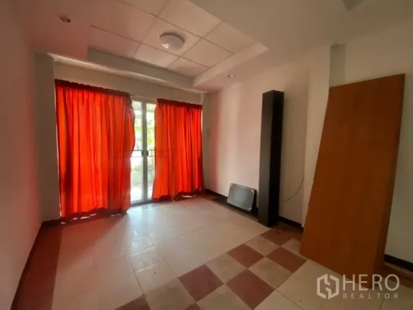 联排别墅 出租在Watthana, Bangkok - 一层房间，推拉玻璃门与红色窗帘，通向前庭。