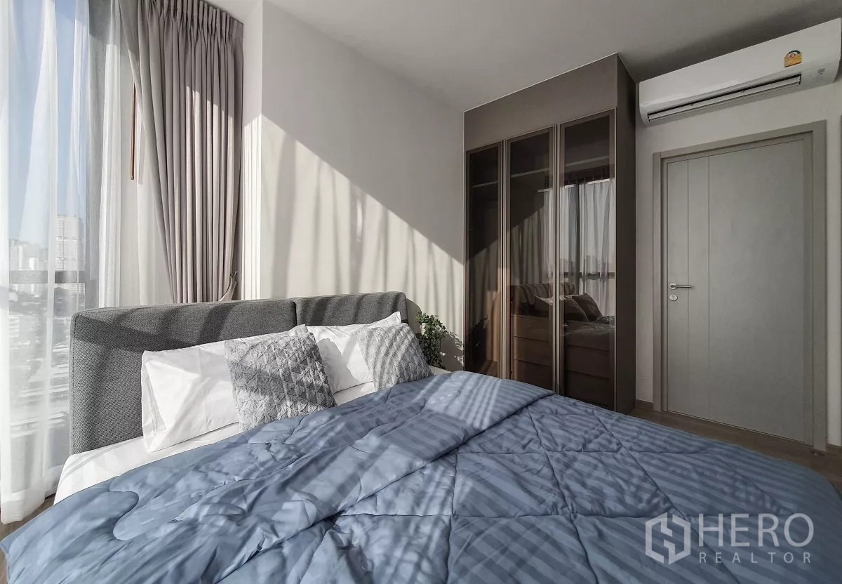 คอนโด ให้เช่าในKhlong Toei, Bangkok - ห้องนอนหลัก หน้าต่างบานใหญ่ หัวเตียงผ้าสีเทา และตู้เสื้อผ้าบานกระจก