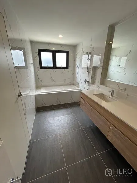 Detached House for rent in Bang Phli, Samut Prakan - Bathroom with bathtub, window and separate shower, marble-pattern walls.