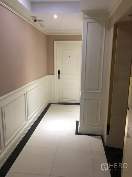 Shophouse for rent or sale in Chatuchak, Bangkok - Quiet corridor with wainscoting leading to a white door and security camera.