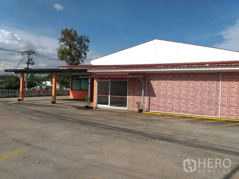 货栈 出租在Khlong Sam Wa, Bangkok - 正立面带砖纹墙与雨棚入口，前方划线停车区。