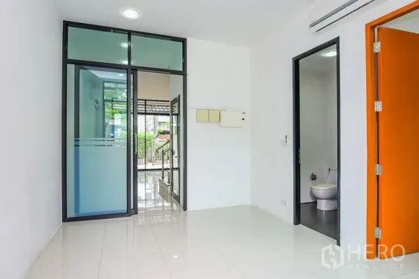 联排别墅 出租在Watthana, Bangkok - 一层入口空间，玻璃推门与亮面地砖，设客用卫生间