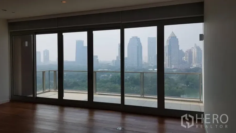 Condominium for rent in Pathum Wan, Bangkok - Living area facing full-height doors to the balcony with a green park outlook.