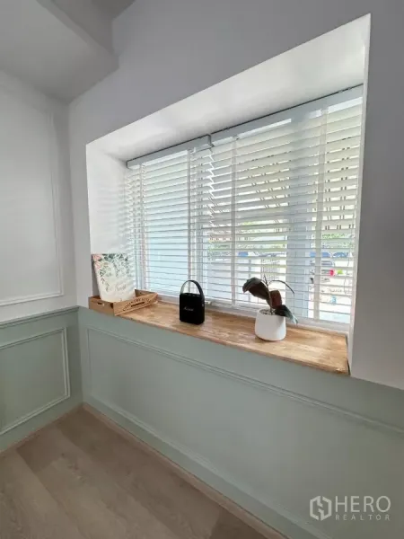 ทาวน์เฮาส์ ให้เช่าในBang Phli, Samut Prakan - มุมหน้าต่างบานกว้างพร้อมมู่ลี่สีขาวและชั้นวางไม้ในห้องนั่งเล่น