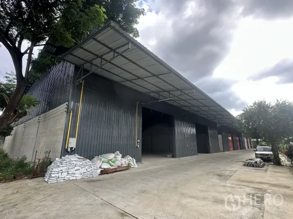 Warehouse for rent in Lam Luk Ka, Pathum Thani - Row of warehouse bays with covered loading canopy and broad driveway for trucks.