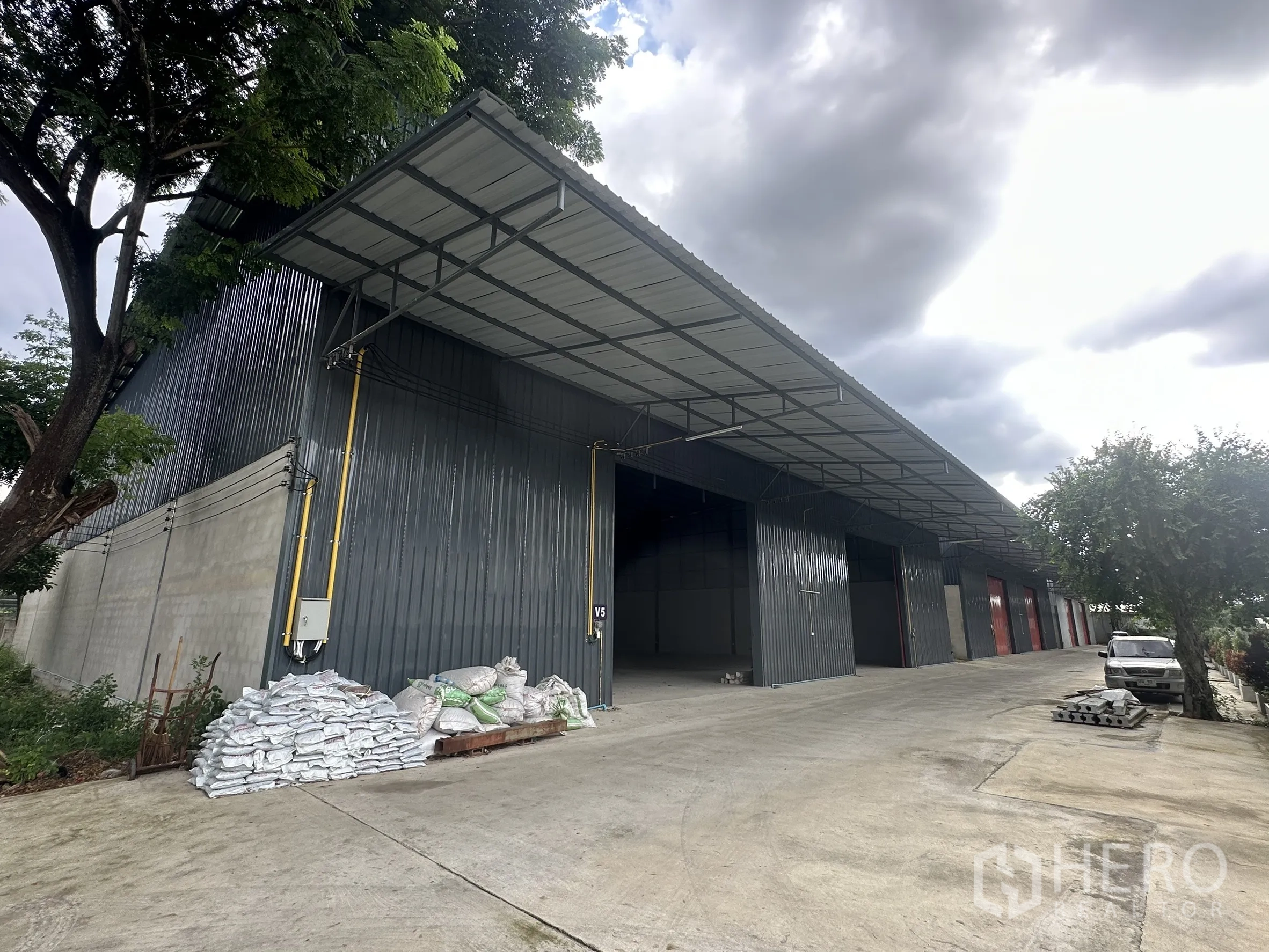 Warehouse for rent in Lam Luk Ka, Pathum Thani - Row of warehouse bays with covered loading canopy and broad driveway for trucks.