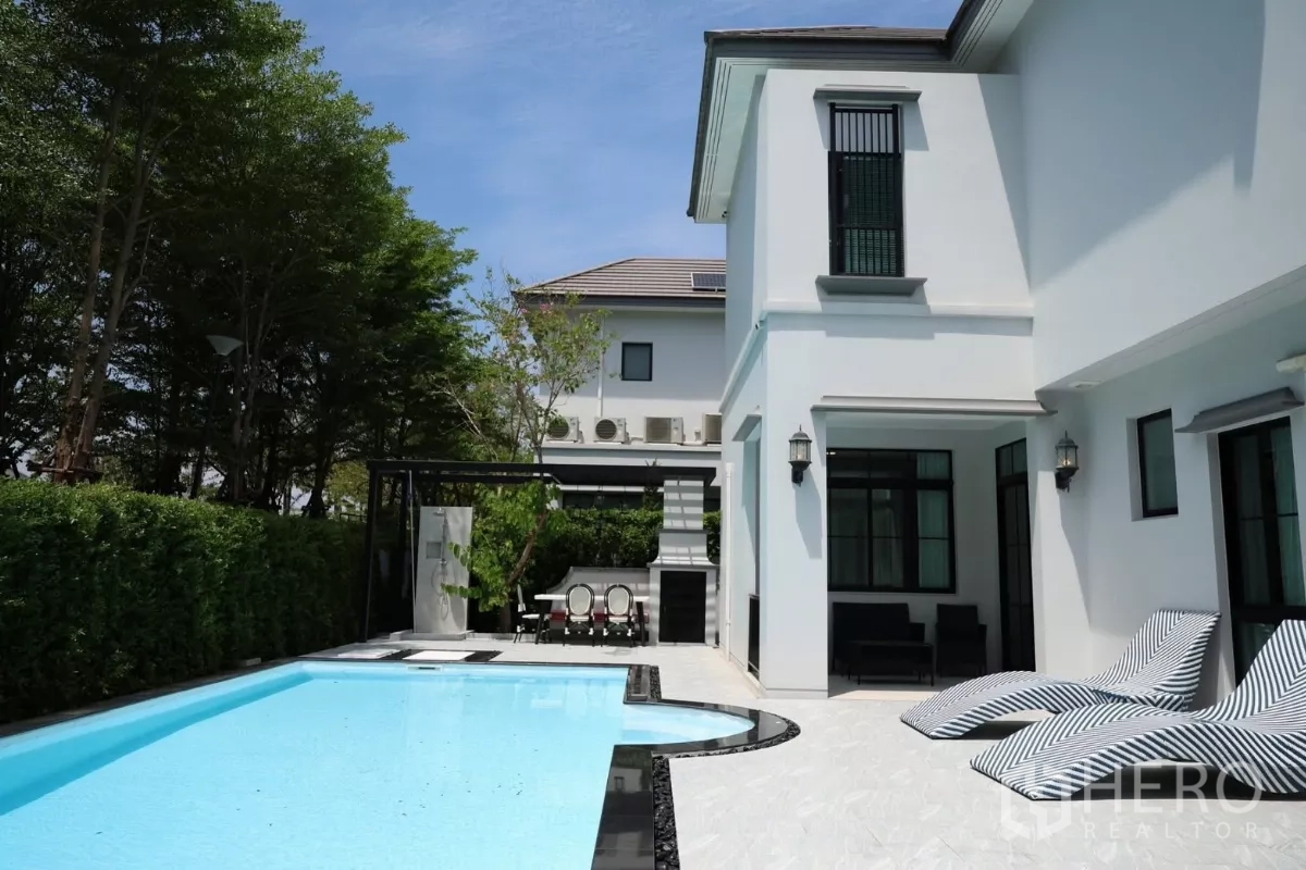 Detached House for rent or sale in Saphan Sung, Bangkok - View of poolside terrace with pergola, outdoor dining area, and hedge-lined boundary.