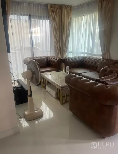 บ้าน ให้เช่าหรือขายในSaphan Sung, Bangkok - มุมห้องนั่งเล่น กระจกบานใหญ่ ม่านโปร่ง โซฟาหนังสีน้ำตาล