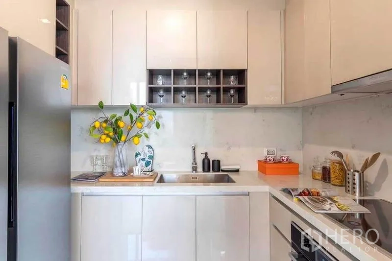 公寓 出租在Watthana, Bangkok - 现代紧凑厨房，白色橱柜、水槽、烤箱与不锈钢冰箱。