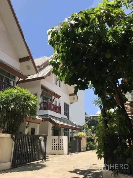 Detached House for rent in Khlong Toei, Bangkok - Exterior of detached house with gated entrance and balconies in a leafy compound.