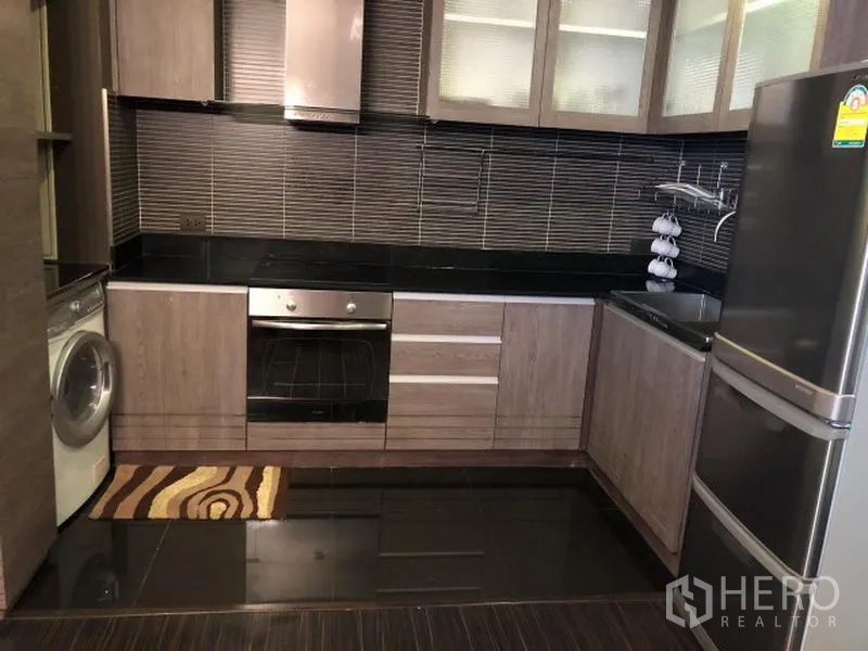 คอนโด ให้เช่าหรือขายในWatthana, Bangkok - ครัวบิลท์อินรูปตัวแอล เคาน์เตอร์สีดำ ผนังกระเบื้อง เตาอบ ตู้เย็น และเครื่องซักผ้า