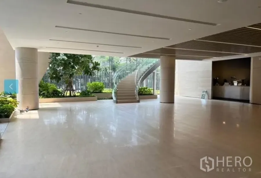 零售空间 出租 - 宽敞现代大堂，石材亮面地坪、落地玻璃、室内绿植与弧形玻璃楼梯。