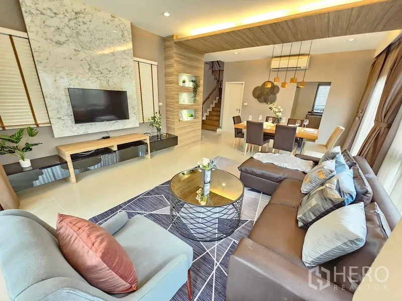 Detached House for rent in Prawet, Bangkok - Open-plan living and dining space with marble TV wall and statement pendant lights.