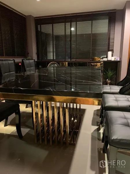 ทาวน์เฮาส์ ให้เช่าในSuan Luang, Bangkok - มุมรับประทานอาหาร โต๊ะหินอ่อนสีดำฐานสีทอง พร้อมเก้าอี้หนังใกล้บานมู่ลี่