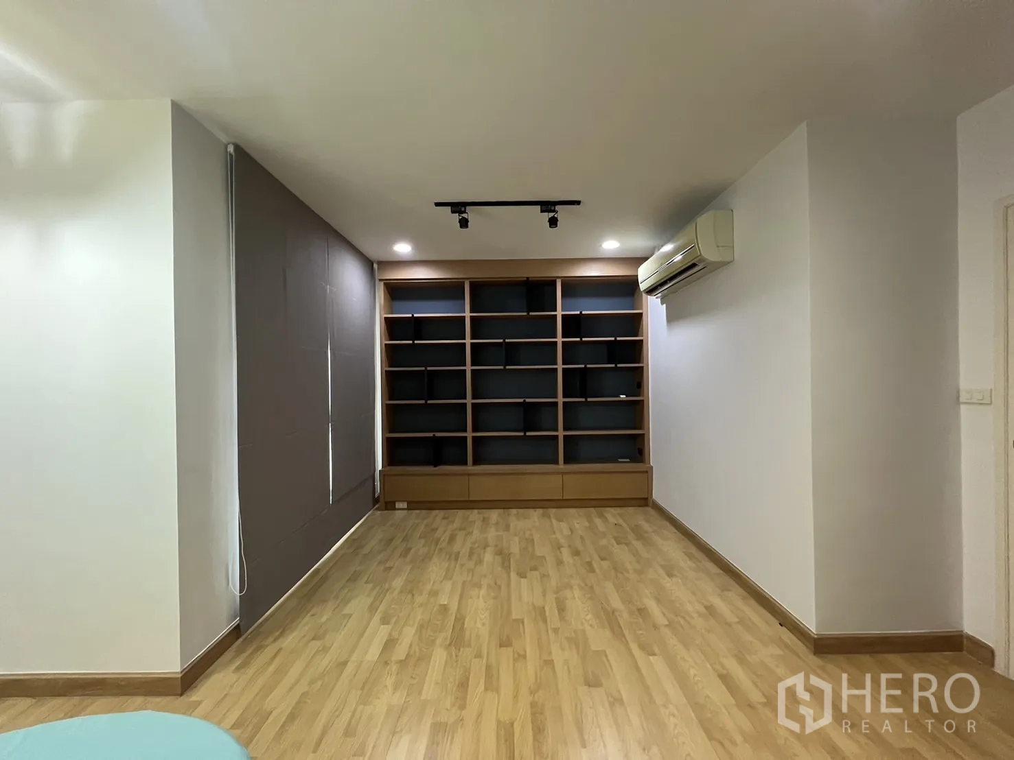 Townhouse for rent in Wang Thonglang, Bangkok - Wide multipurpose room with long wall of shelving and track lights.