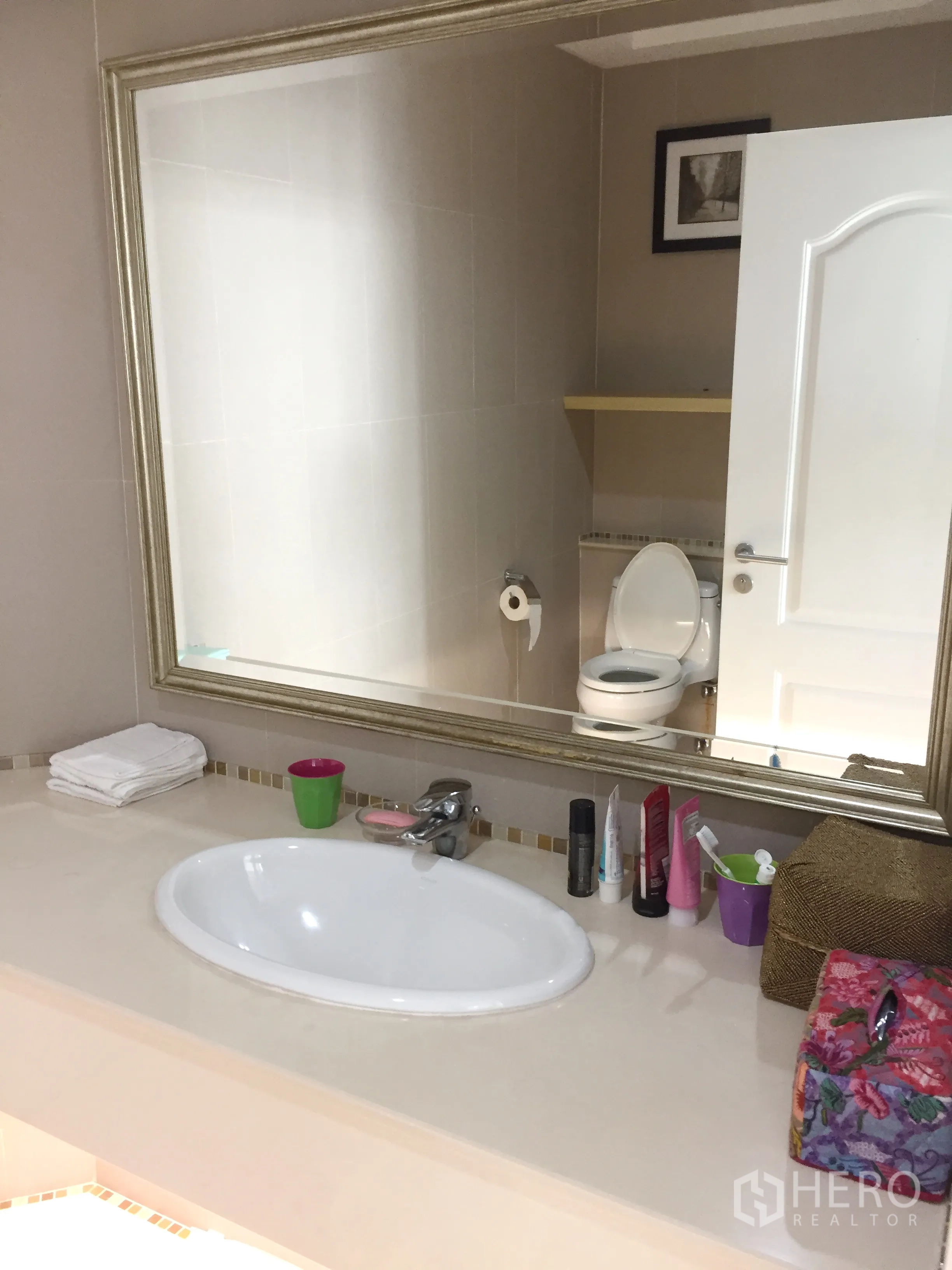 Townhouse for rent in Khlong Toei, Bangkok - Vanity area with a large framed mirror, sink counter and adjacent toilet in a neutral‑tone bathroom.