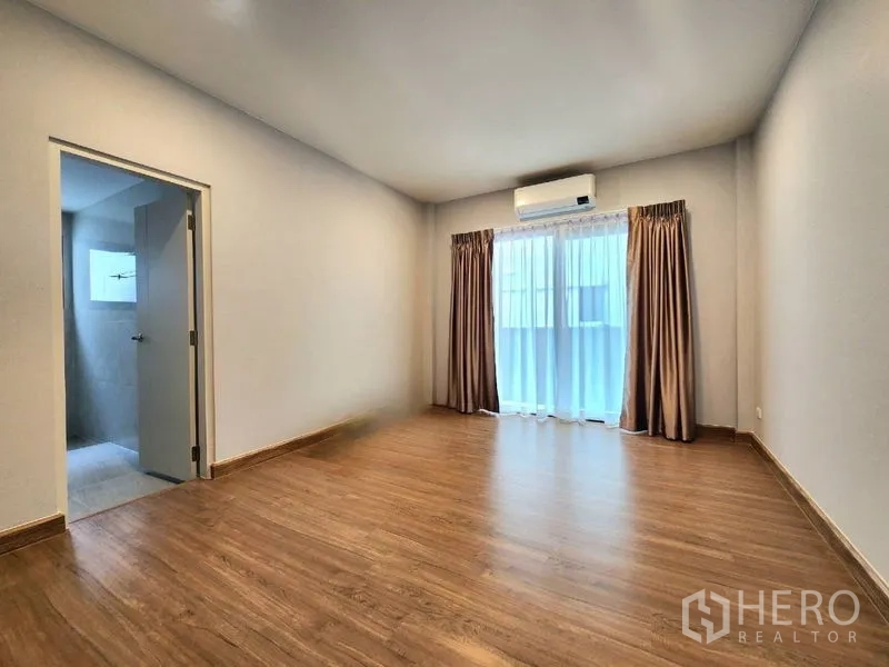 Detached House for rent in Bang Phli, Samut Prakan - Bright bedroom with balcony door, air conditioning and en-suite bathroom.