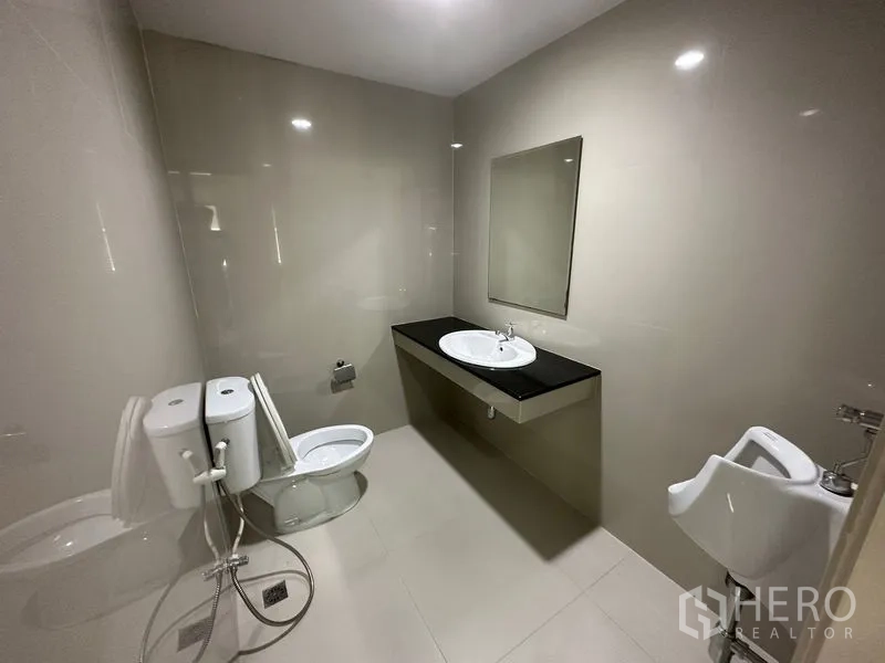 办公空间 出租 - 干净的办公卫生间，配有坐便器、小便池、台盆和墙镜。