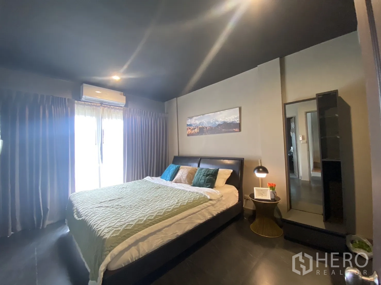 Townhouse for rent in Bang Kapi, Bangkok - Master bedroom with sliding balcony doors, AC and dark flooring.