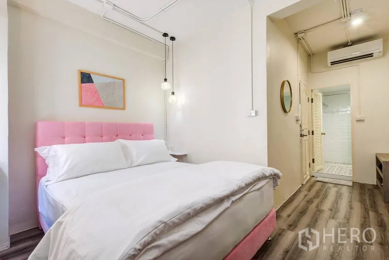 Townhouse for rent in Bang Rak, Bangkok - Cozy bedroom with a pink headboard, pendant lights, and ensuite entry.