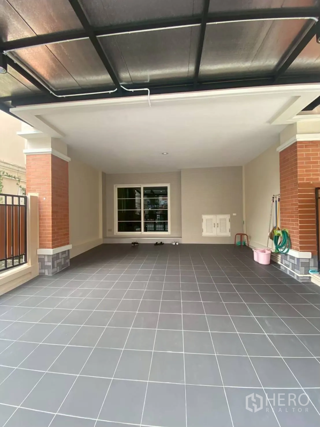 Townhouse for rent in Bang Kapi, Bangkok - Covered carport with gray floor tiles and gated entry.