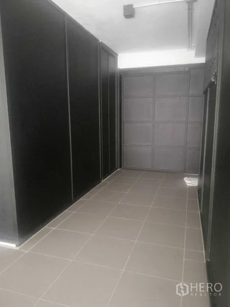 Shophouse for rent in Khlong Toei, Bangkok - Narrow corridor with dark built-in panels and gray floor tiles.