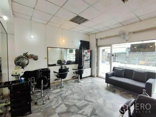 Townhouse for sale in Bang Phlat, Bangkok - Ground-floor open space with salon setup, marble tile floor, wall mirrors and glass frontage.