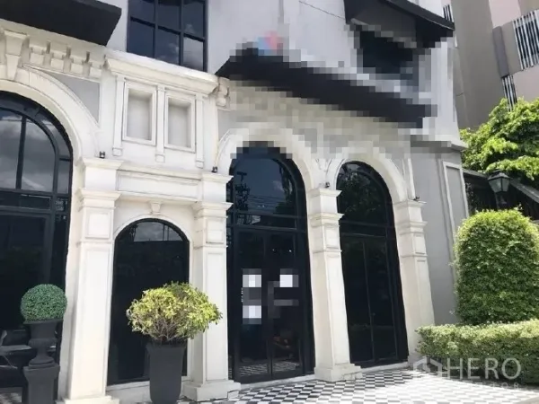 零售空间 出租在Huai Khwang, Bangkok - 零售店面特写，高挑拱形玻璃门、白色立面线条与棋盘格入口，配有绿植。